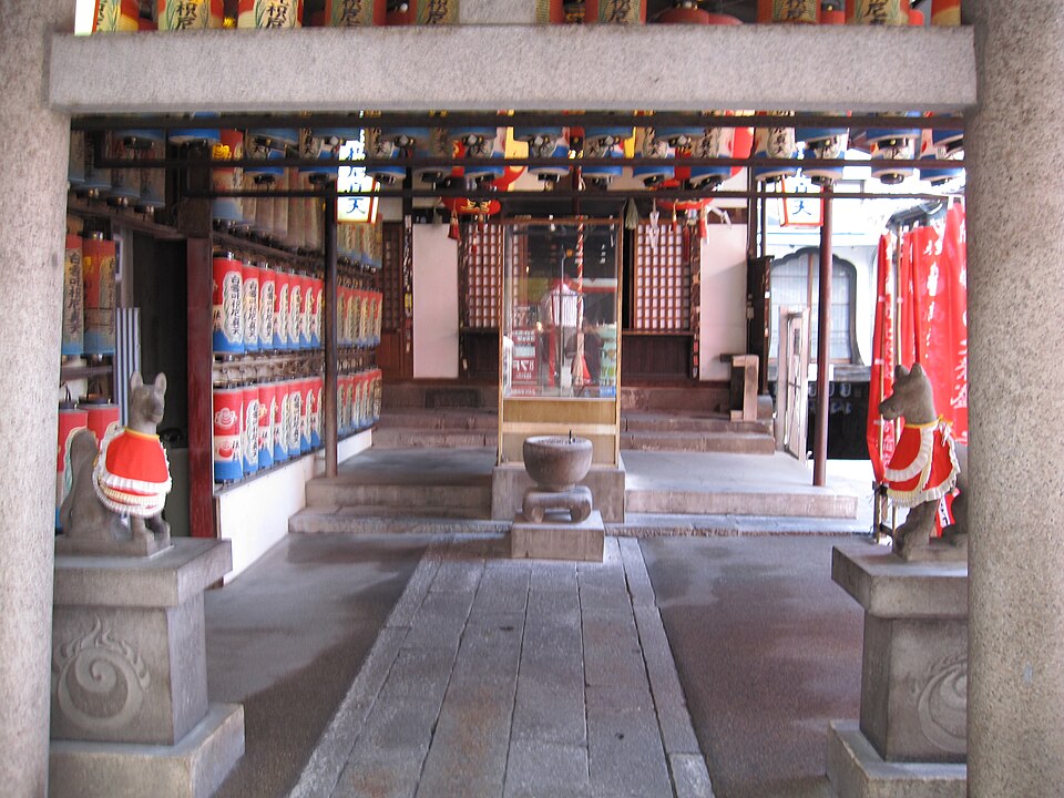萬松寺境內，兩側排列奉納酒樽與紅色幟旗，前方有狐狸石像